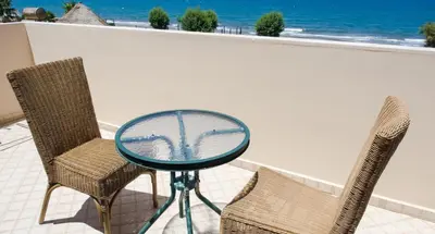 a glass table and chairs on a balcony with the ocean at Alexandra SeaSide Villas in Plataniás