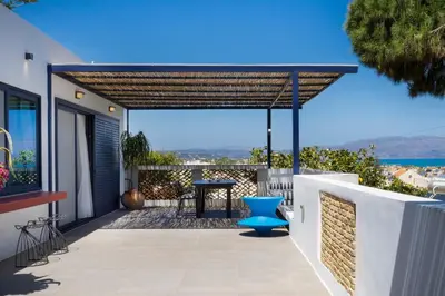 a pergola on a balcony with a table and a blue chair at Cretan Loft in Plataniás