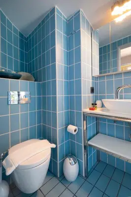 a blue tiled bathroom with a toilet and a sink at Cretan Loft in Plataniás