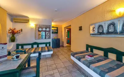 a room with two beds and a table and a dining room at Castle Suites Hotel in Plataniás