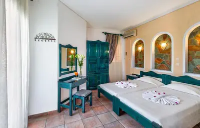 a hotel room with two beds and a desk at Castle Suites Hotel in Plataniás