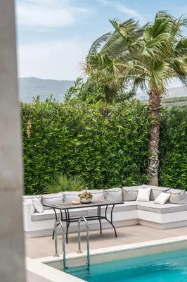 a table and chairs next to a pool with a palm tree at Miraida Exclusive Residence in Almirida