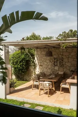 a patio with a table and chairs and a stone wall at Miraida Exclusive Residence in Almirida