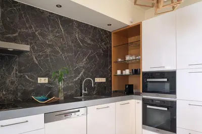 a kitchen with white cabinets and a black counter top at Miraida Exclusive Residence in Almirida