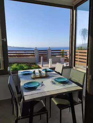 a dining room with a table and chairs and a large window at Wish Sea & Mountain View in Stalos