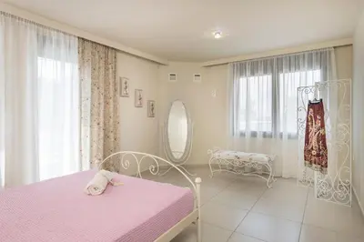 a bedroom with a pink bed and a mirror at Villa Antoni in Galatás