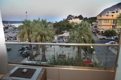 a balcony with a view of a street with palm trees at Oneiro Suites in Souda