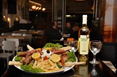 a plate of food on a table with a bottle of wine at Oneiro Suites in Souda