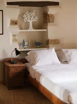 a bedroom with a bed and a table with a lamp at Casa Olea - A Venetian era Home with Courtyard in Kondomari