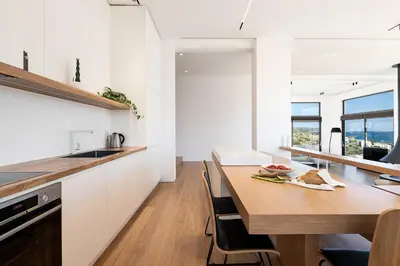 a kitchen with a wooden table and white cabinets at Seametry Luxury Living Penthouse in Souda
