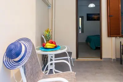 a table with a bowl of fruit and a hat on a chair at Apolafsi Apartments 2 New with kitchen in Chania Town