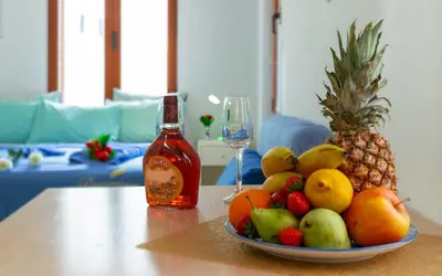 a bowl of fruit on a table with a bottle of alcohol at Apolafsi Apartments 1New with kitchen in Chania Town