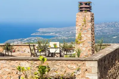 a stone wall with a table and chairs and a lighthouse at Traditional Crete Villa Villa Green Faskomilia Stunning Views 1 Bedroom in Khiliomoudhoú