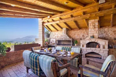 a patio with a table and a stone fireplace at Samonas Traditional Villas Purple Villa Malotira - 85M² Maisonette in Khiliomoudhoú
