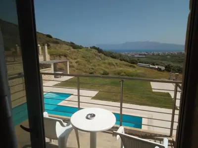 a balcony with a table and chairs and a pool at Villa Stylianos retreat in Kissamos