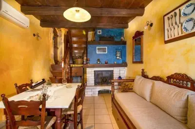 a dining room with a table and a couch and a fireplace at Traditional Crete Villa Villa Blue Mantzourana Stunning Views 1 Bedroom in Khiliomoudhoú