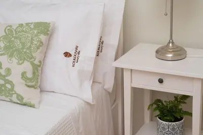 a bed with white sheets and a pillow next to a table at Luxury Crete Villa Villa Koukounari Private Pool Beautiful Scenery in Chania Town