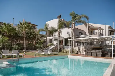 a swimming pool in front of a house with palm trees at Villa Anemeli - Luxury pool villa with gorgeous seaview in Kissamos