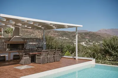 a patio with a table and chairs and a fireplace at Villa Anemeli - Luxury pool villa with gorgeous seaview in Kissamos