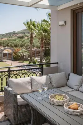 a patio with a couch and two glasses of wine at Villa Anemeli - Luxury pool villa with gorgeous seaview in Kissamos