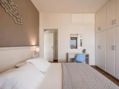 a bedroom with a white bed and a blue chair at Villa Anemeli - Luxury pool villa with gorgeous seaview in Kissamos