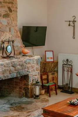 a living room with a stone fireplace with a television at Villa Kalamitsi Luxury Villa in Apokorona Chania in Kariá