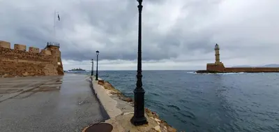 a street lights next to the water with a lighthouse at Lektron Apartment in Chania Town