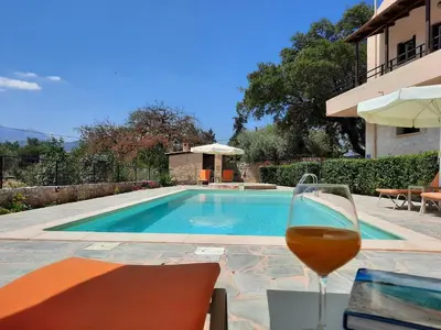 a glass of wine sitting next to a swimming pool at Villa Maragoudi in Arménoi