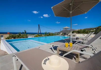 a villa with a swimming pool with a table and chairs at Petras Resort in Falasarna