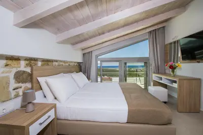 a bedroom with a large bed and a large window at Petras Resort in Falasarna