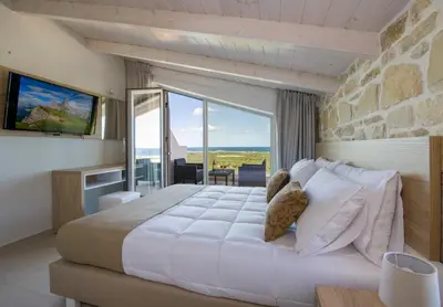 a bedroom with a large bed and a large window at Petras Resort in Falasarna