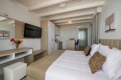 a bedroom with a large white bed and a television at Petras Resort in Falasarna