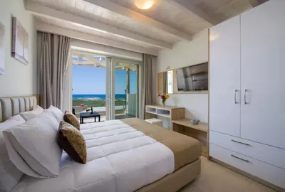 a bedroom with a bed and a view of the ocean at Petras Resort in Falasarna
