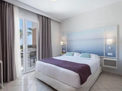 a bedroom with a large bed and a balcony at Caldera Beach in Plataniás