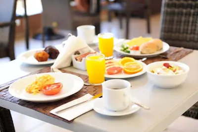 a table with plates of food and cups of orange juice at Caldera Bay in Plataniás