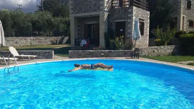 a man laying in a large swimming pool at Stratos Villas in Melidhónion