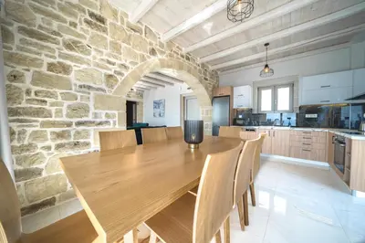 a dining room with a wooden table and a stone wall at Nafsika Xenia Villa in Plátanos