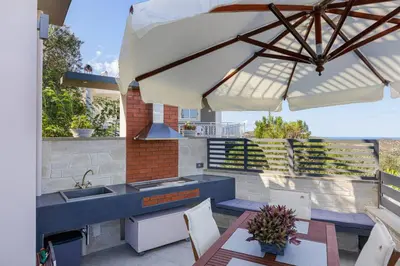 a patio with a sink and a kitchen with an umbrella at Villa Chryssi in Kissamos