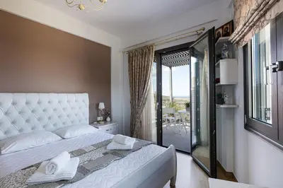 a bedroom with a large white bed and a balcony at Villa Chryssi in Kissamos