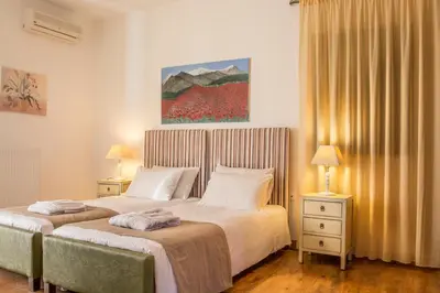 a bedroom with two beds and two lamps and a painting at Villa Kalithea in Pemónia