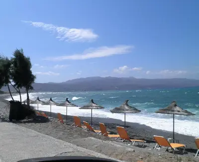 a group of chairs and umbrellas on a beach at Haridimos Apartments in Tavronitis