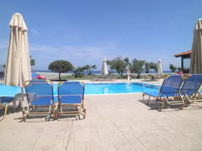 a group of chairs and umbrellas next to a pool at Haridimos Apartments in Tavronitis