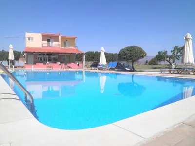 a large blue swimming pool in front of a house at Haridimos Apartments in Tavronitis