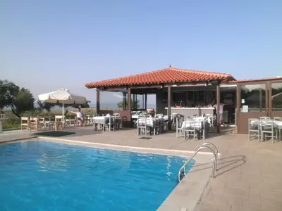 a swimming pool with tables and chairs and a restaurant at Haridimos Apartments in Tavronitis