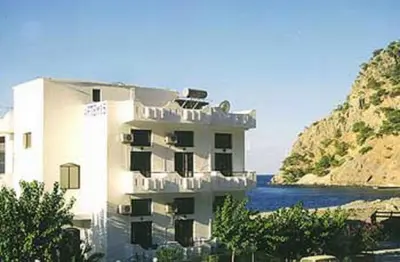 a white building next to a body of water at Artemis Studios in Agia Roumeli