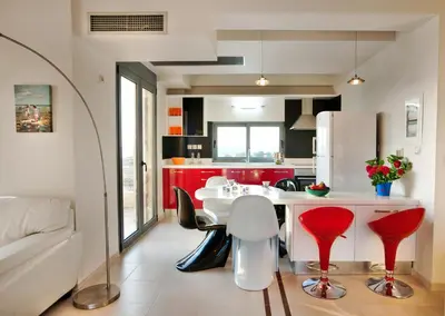 a kitchen with red cabinets and a white table and chairs at Anemon Villas in Kissamos