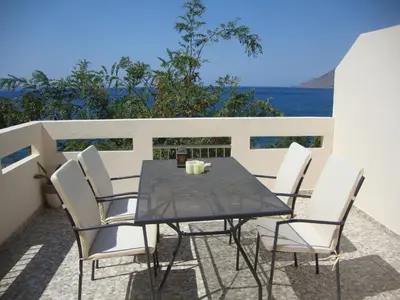 a table and chairs on a balcony with the ocean at Ravdoucha Beach Studios in Ravdhoúkha