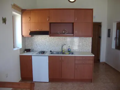 a kitchen with wooden cabinets and a white refrigerator at Ravdoucha Beach Studios in Ravdhoúkha