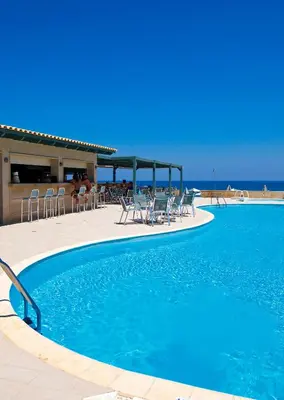 a swimming pool with chairs and the ocean in the background at Lissos Beach in Plataniás