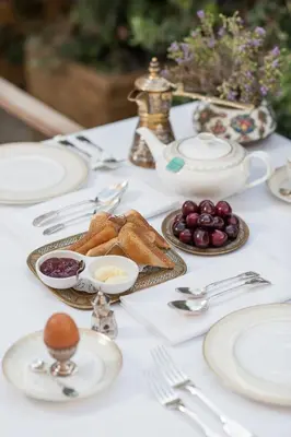 a white table topped with plates and silver utensils at La Maison Ottomane in Chania Town